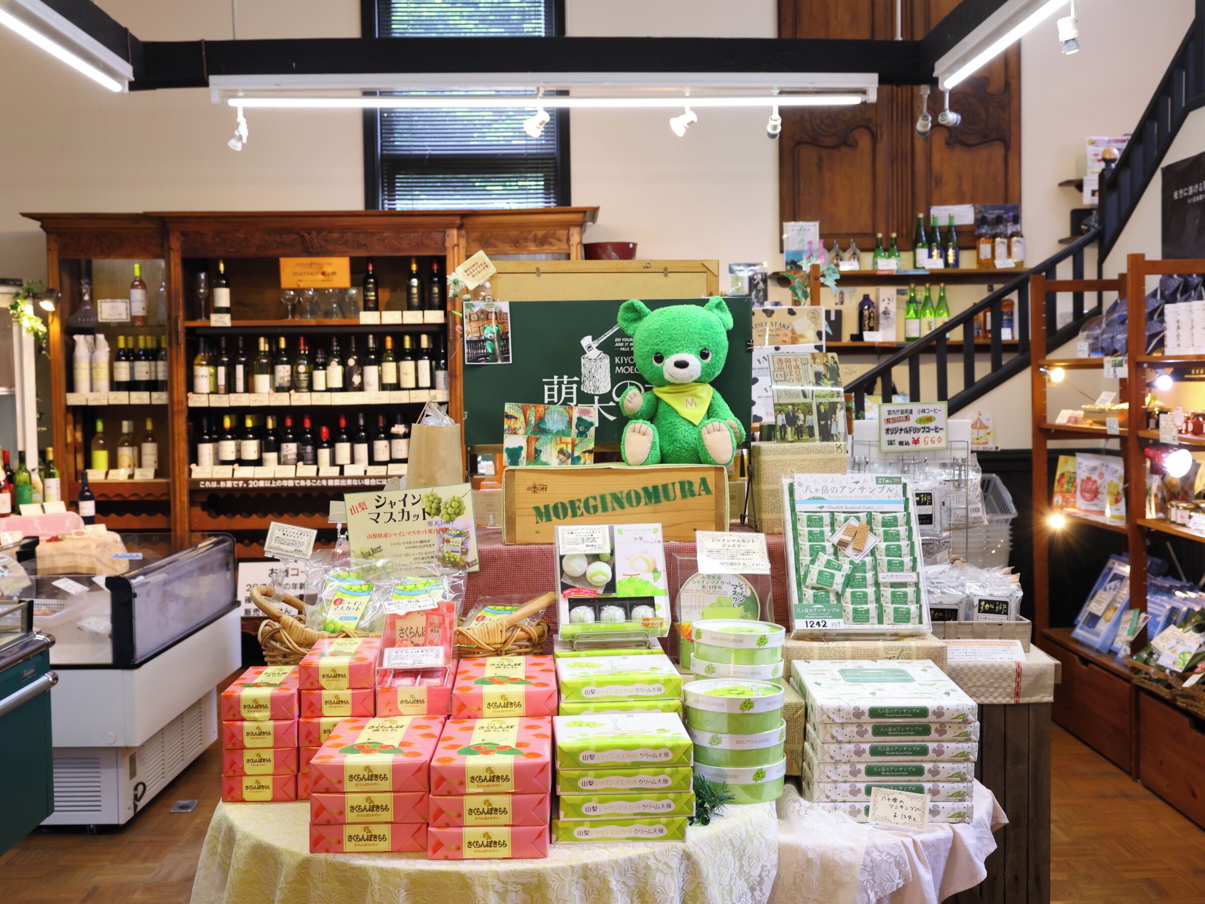 Una tienda con una variedad de productos, incluyendo artículos en caja, un osito de peluche y botellas de vino.