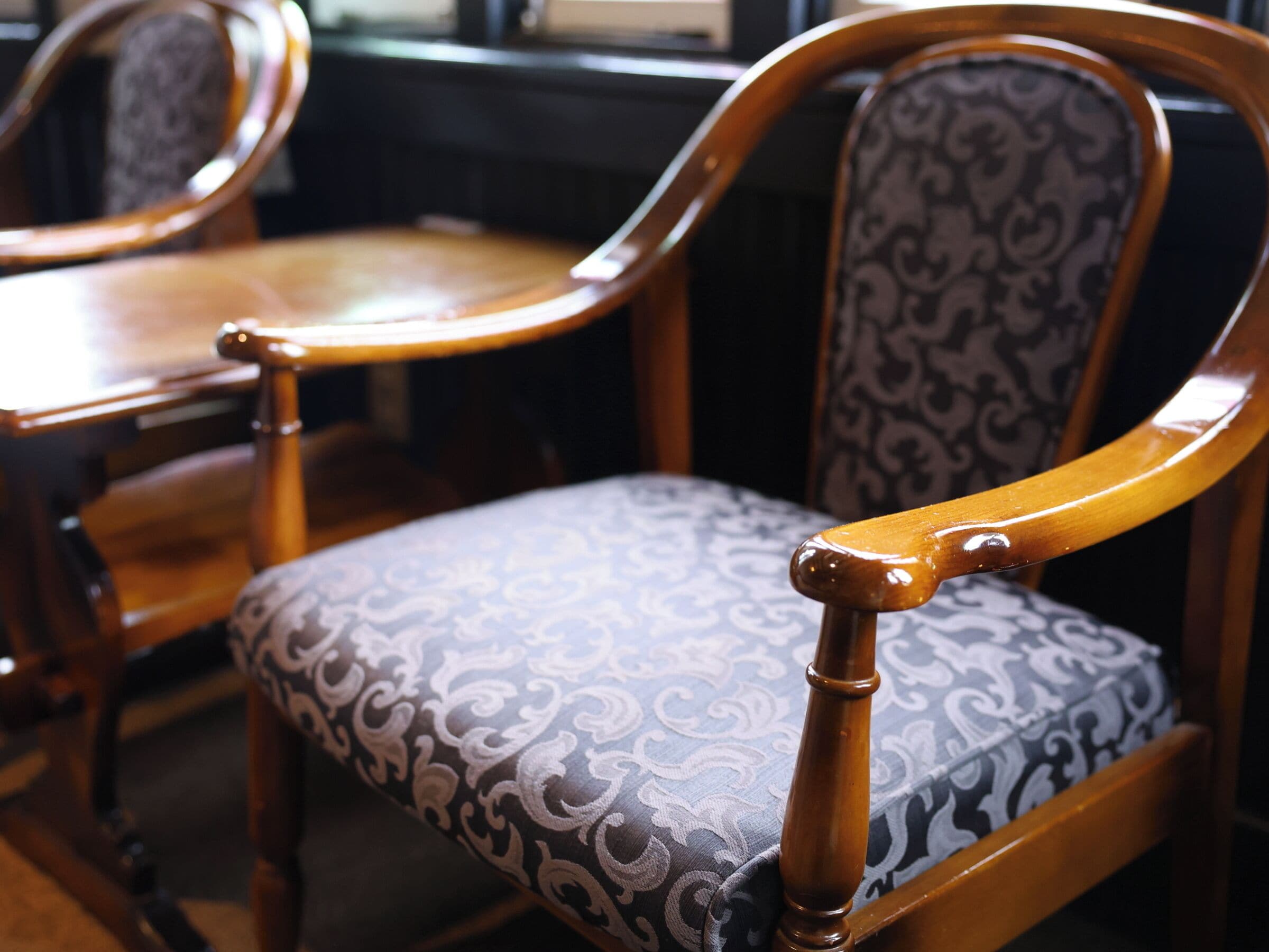 A wooden chair with a cushioned seat and backrest, featuring a patterned fabric.