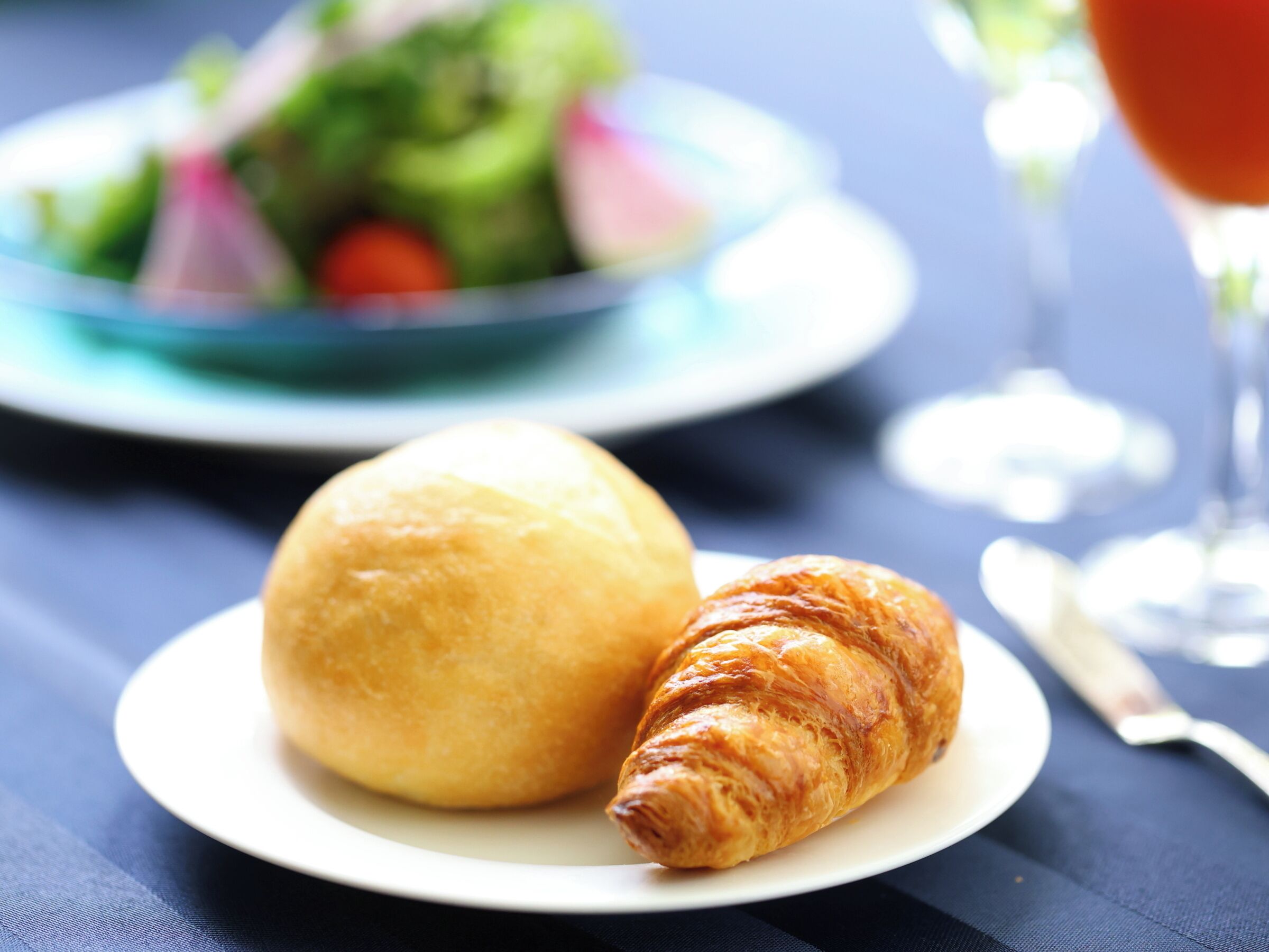 Une assiette avec un croissant et un petit pain rond, posée sur une table.