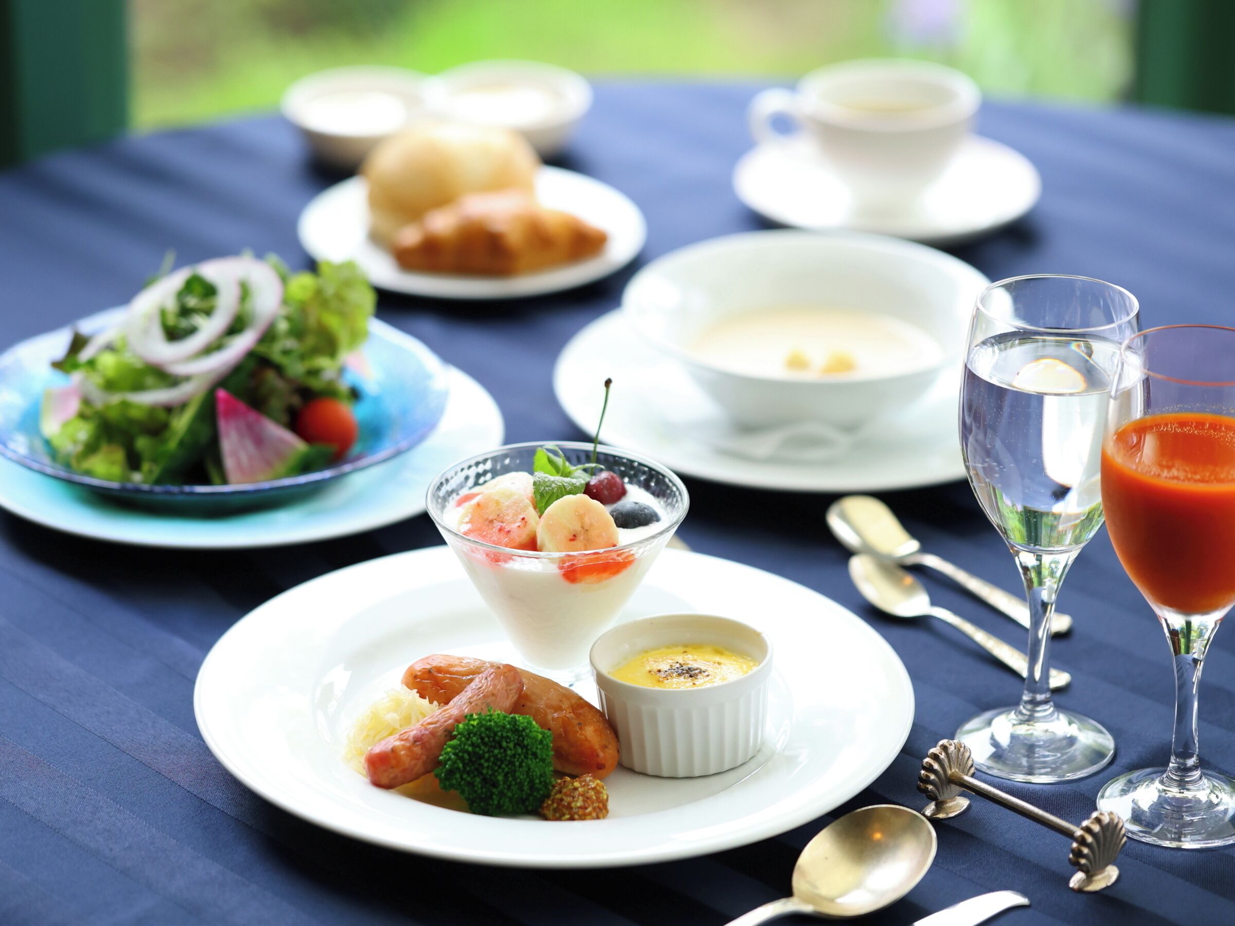 A table set with various dishes including a salad, soup, and a glass of juice.