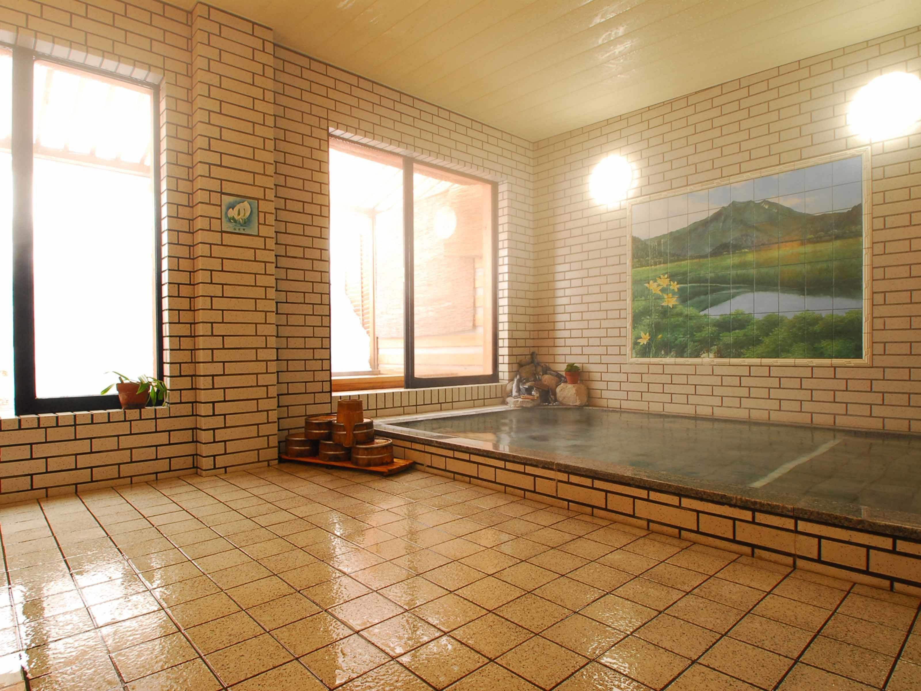 Una habitación con pared de ladrillo, un ventanal grande, un cuadro y suelo de baldosas.