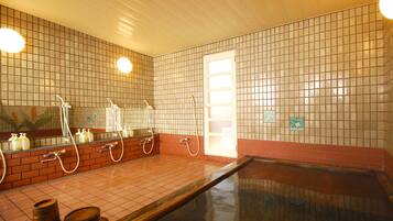 A spa area with a large pool, a shower area with multiple faucets, and a tiled wall with a grid pattern.