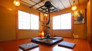 A traditional Japanese room with tatami flooring, shoji screens, and a hanging water feature.