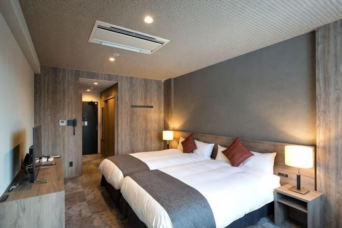 A hotel room with a large bed, bedside lamps, a desk, and a TV.