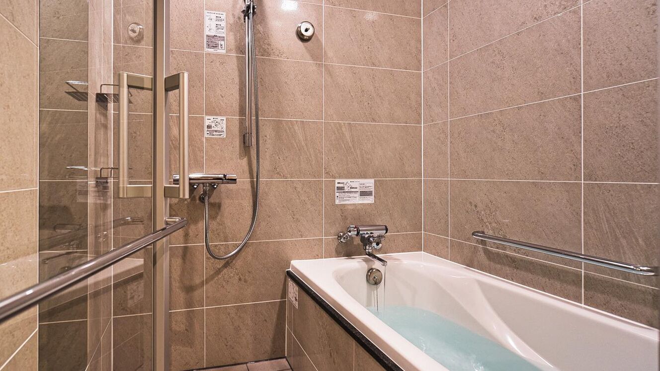 Une salle de bain avec une douche à parois de verre, une baignoire et des murs carrelés.