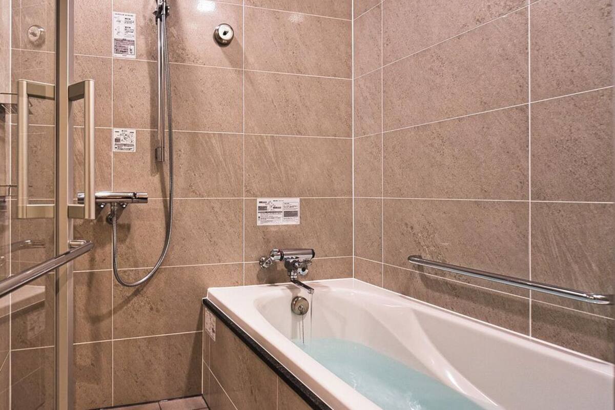 Ein Badezimmer mit Duschkabine aus Glas, einer Badewanne und gefliesten Wänden.