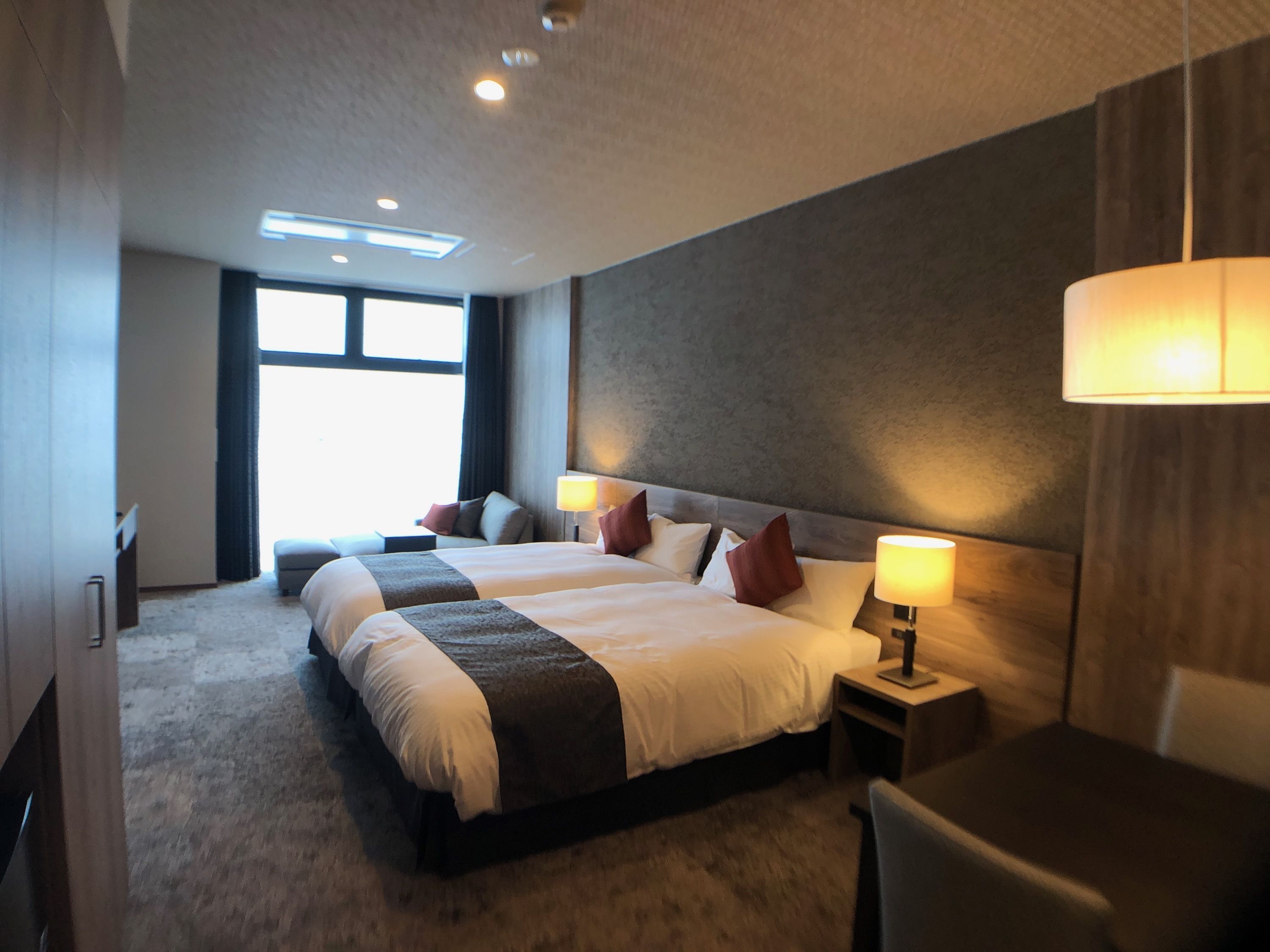 A hotel room with a large bed, two bedside tables, a desk, and a chair.