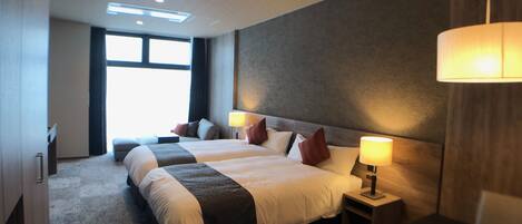 A hotel room with a large bed, two bedside tables, a desk, and a chair.