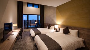 Hotellihuone, jossa on kaksi sänkyä, työpöytä ja näkymä kaupungin ylle.