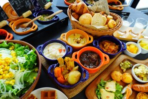 Une variété de plats, notamment des soupes, des salades et du pain, présentés sur une planche en bois.