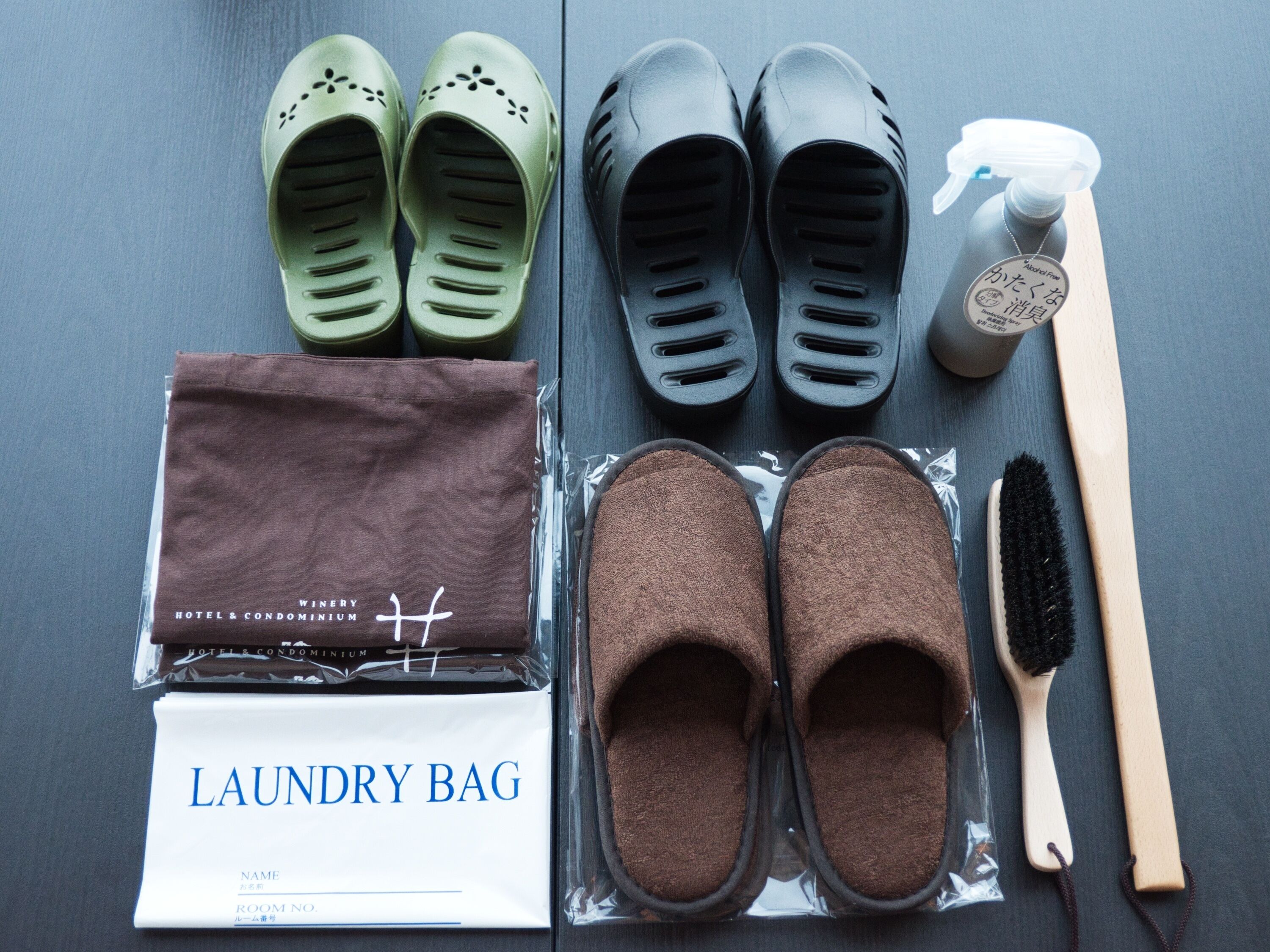 A set of slippers, a spray bottle, a brush, a brown bag, and a white bag with "LAUNDRY BAG" text.