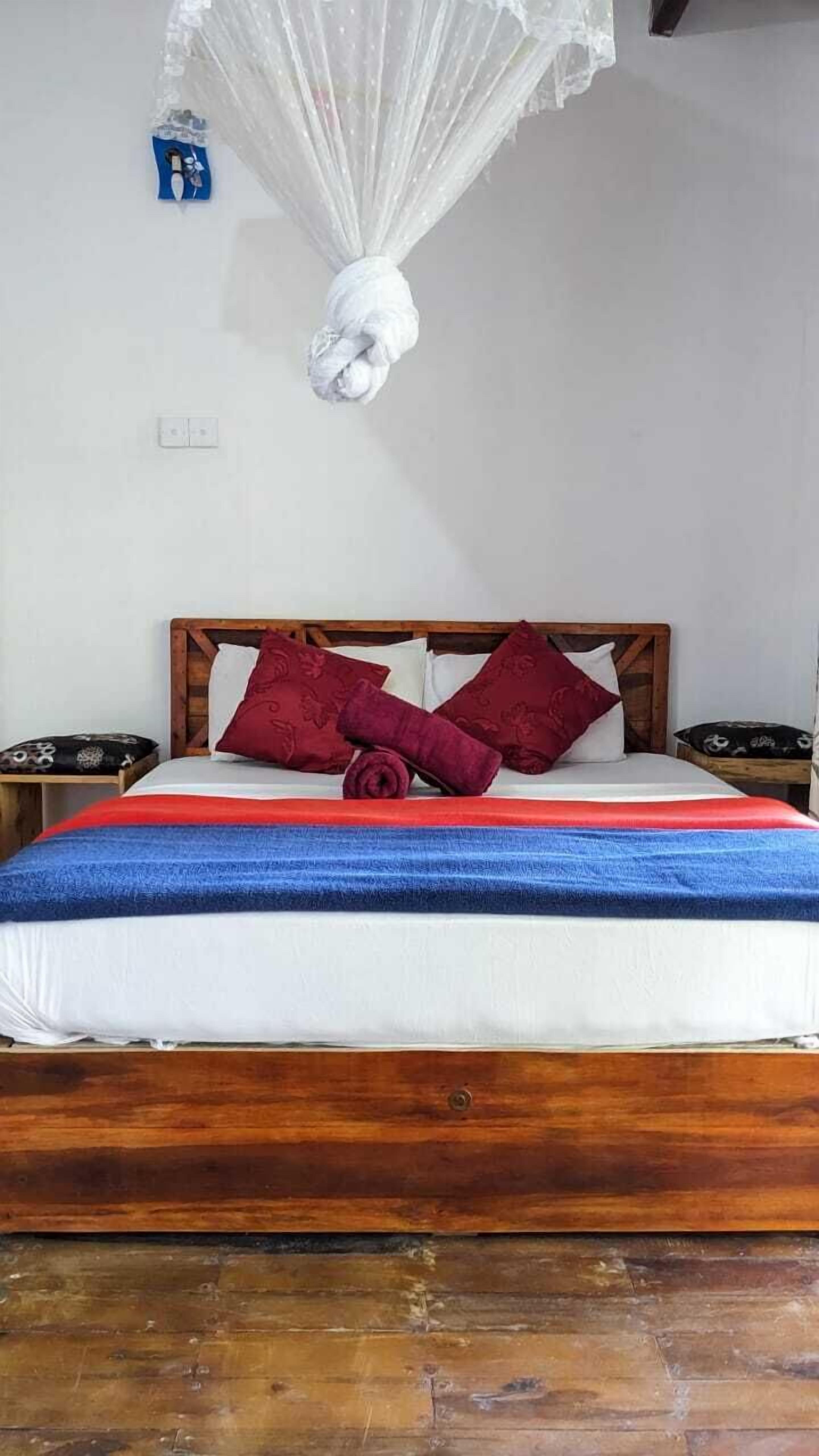 A bed with a wooden headboard, a white mattress, and a blue and red blanket.