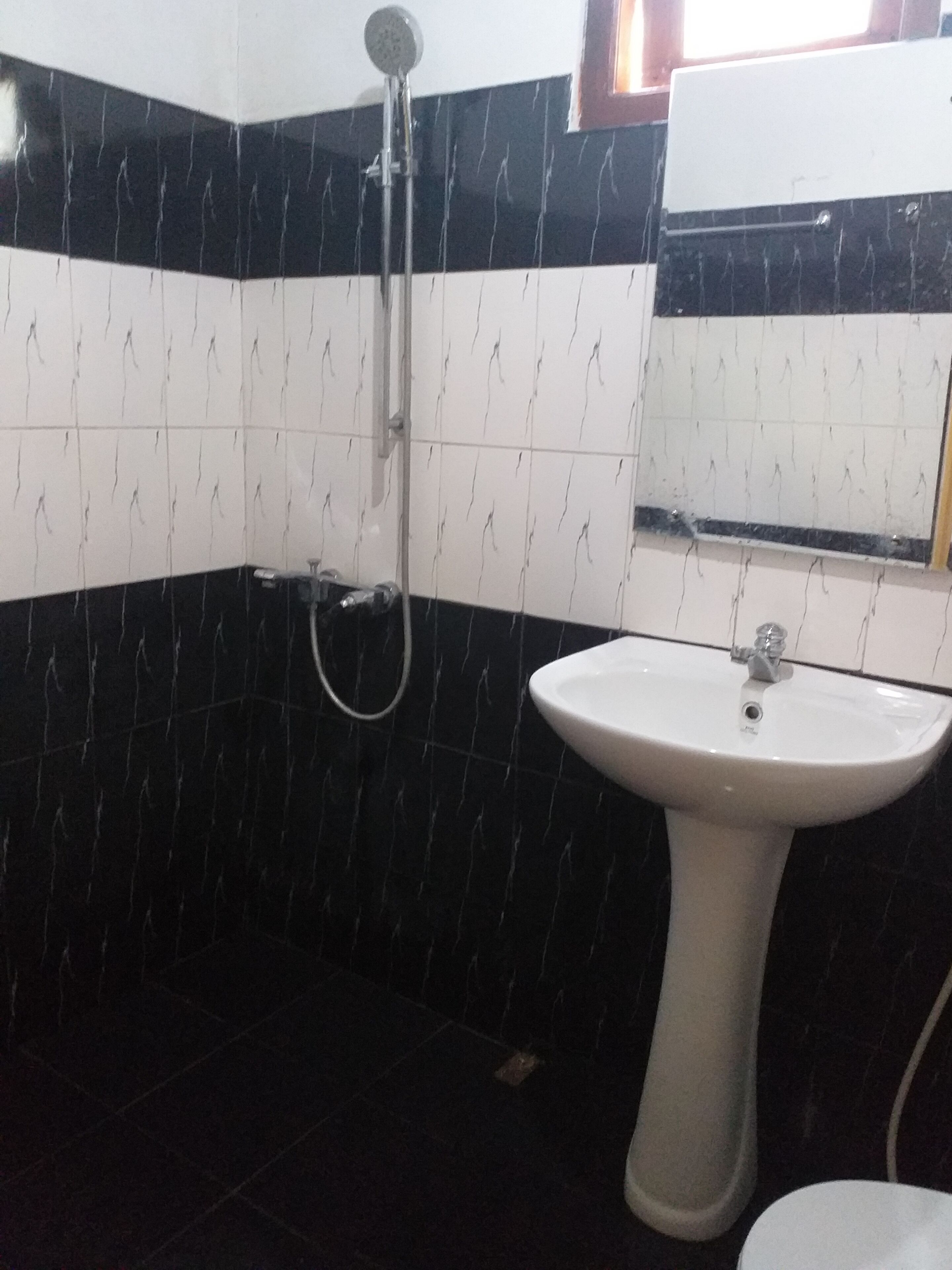 A bathroom with a white sink, black and white tiled walls, and a shower.