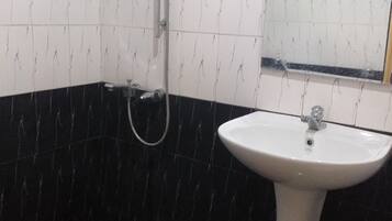 A bathroom with a white sink, black and white tiled walls, and a shower.