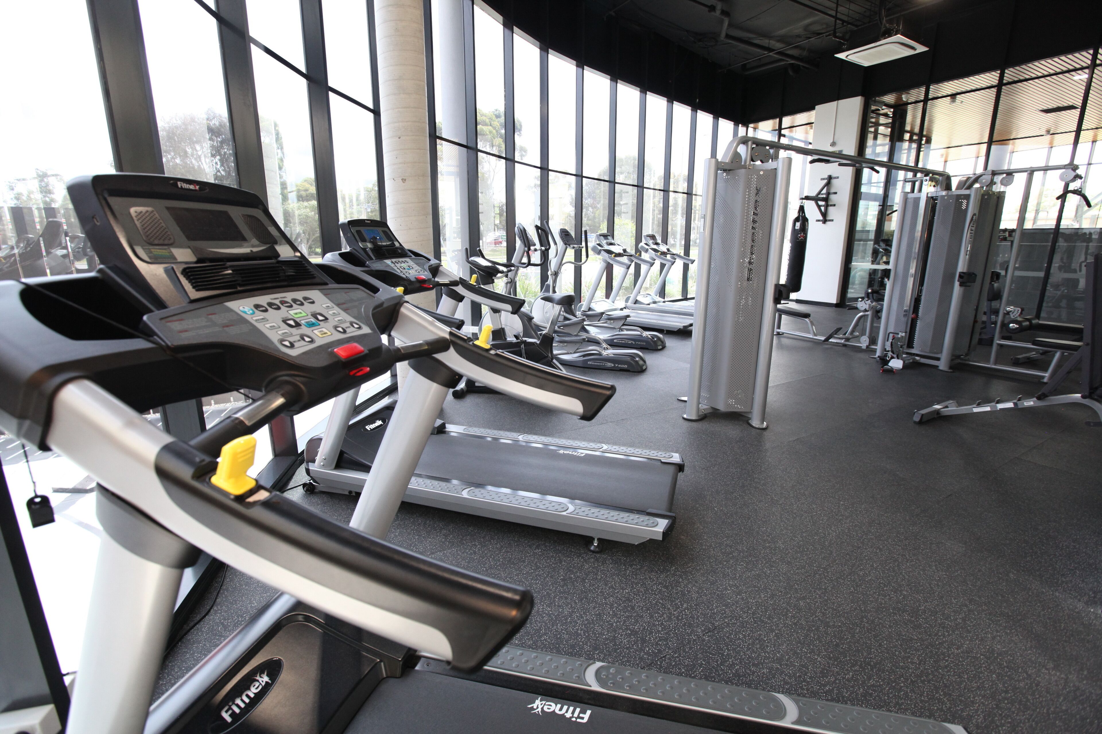 A gym with treadmills, weight machines, and a control panel.