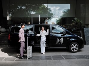 A black van with "HOTEL" and a logo on the side parked in front of a building with steps leading up to it. - M Hotel Saigon (Ho Chi Minh City)