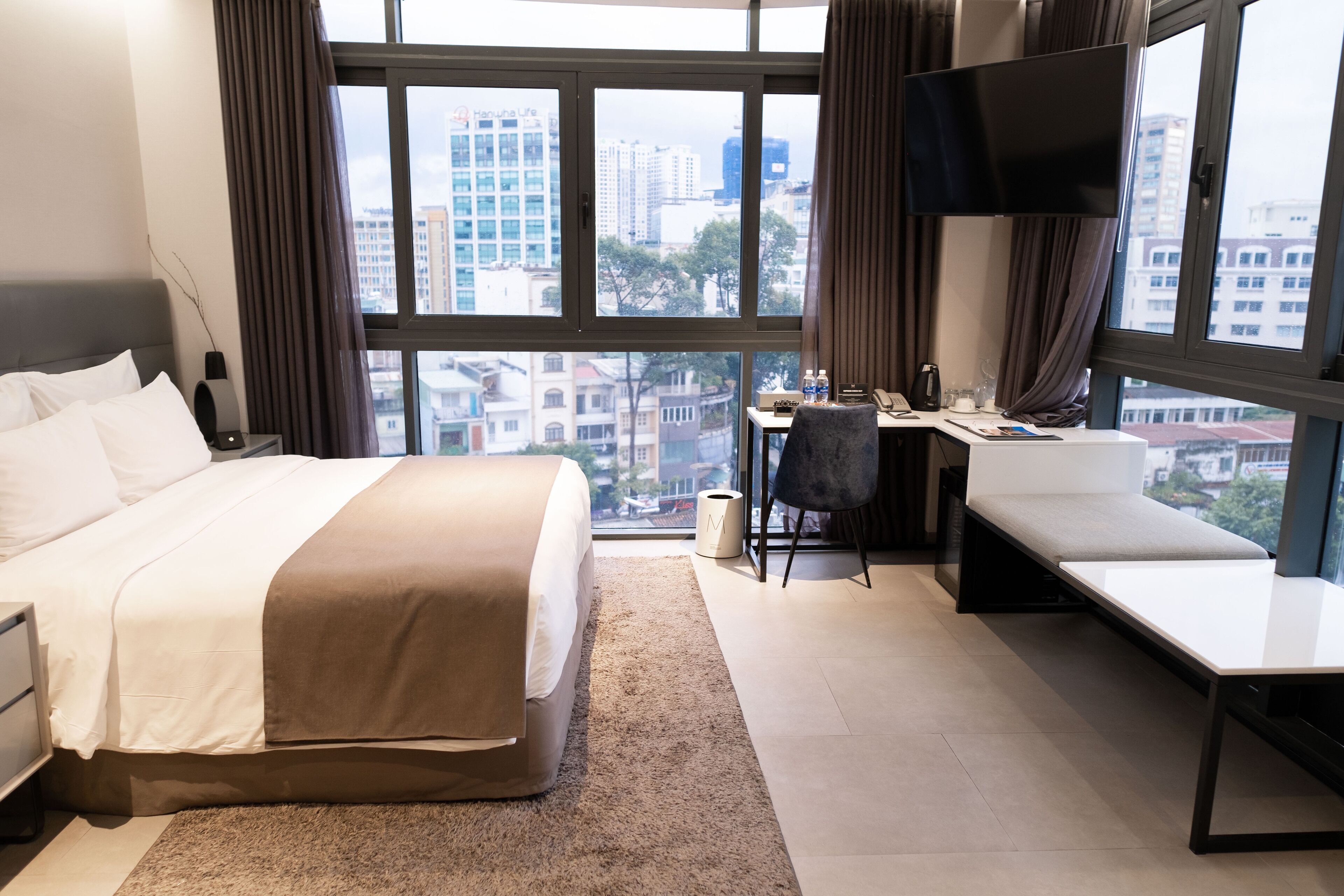 A modern hotel room with a large bed, a desk, and a sofa.