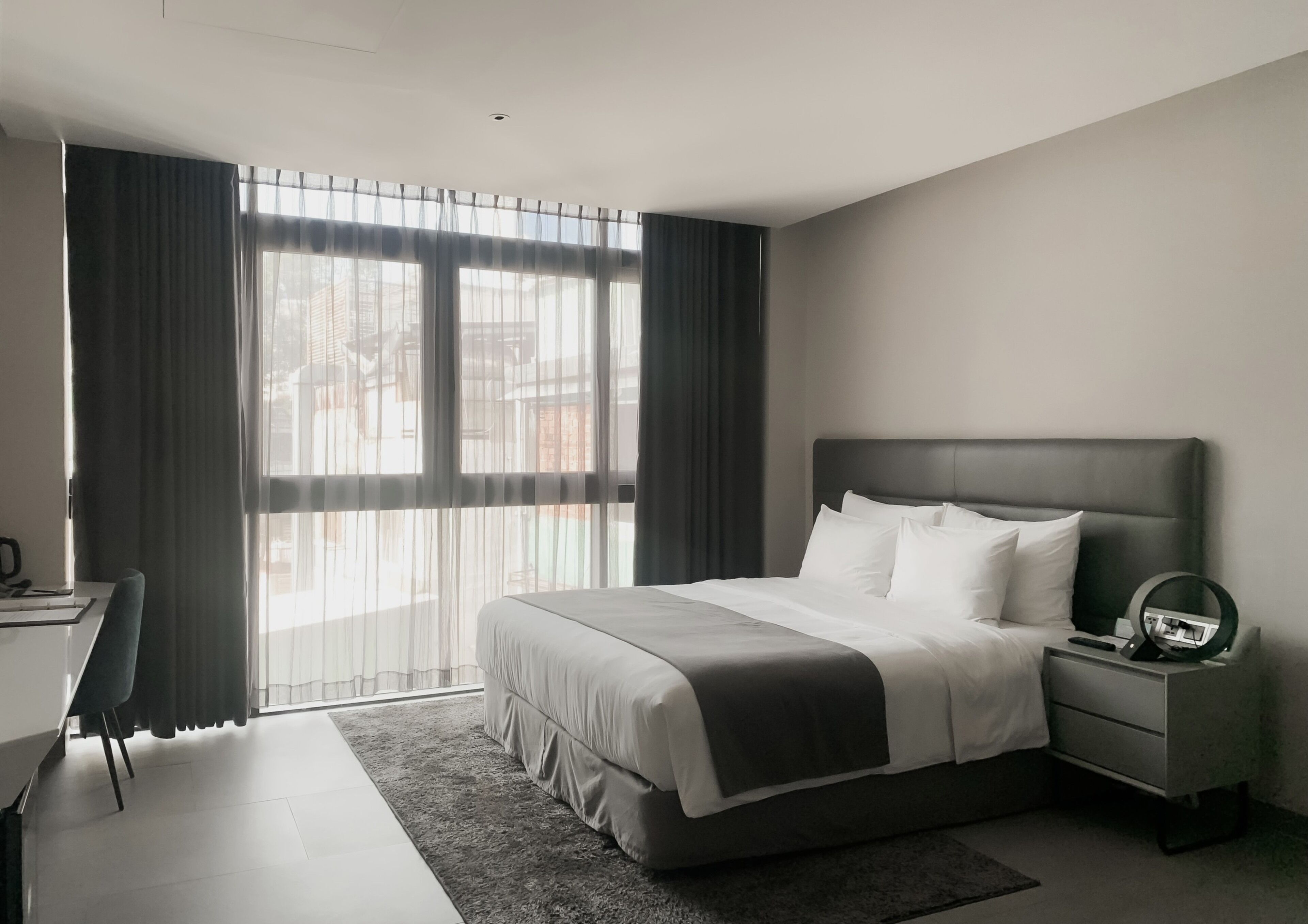 A modern hotel room with a large bed, a desk, and a chair.