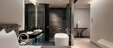 A modern hotel bathroom with a large bathtub, a separate shower area, and a vanity with a mirror.