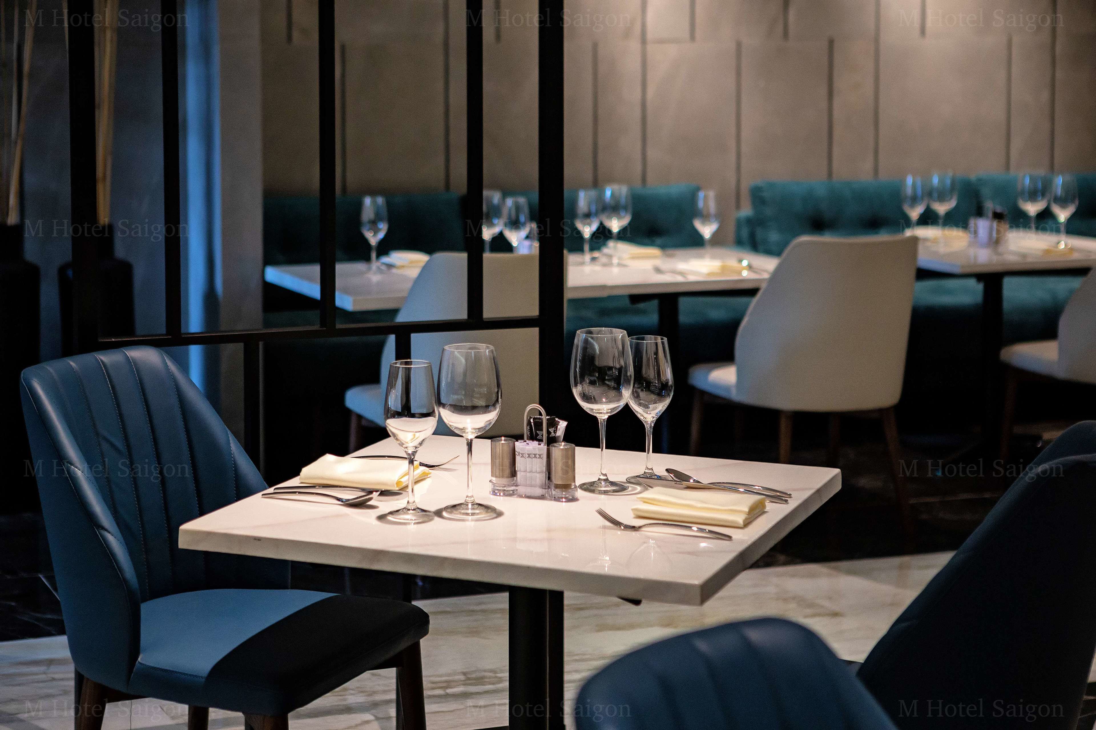 Un restaurant dont les tables sont dressées pour le service, avec verres à vin et couverts.