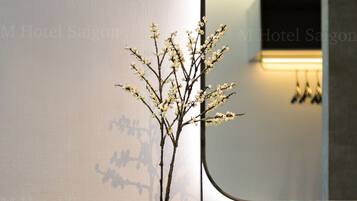 A modern bathroom with a vase of white flowers, a mirror, and a white sink.