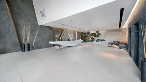 Un vestíbulo amplio con una moderna recepción, zona de estar y una pared con jardines verticales.