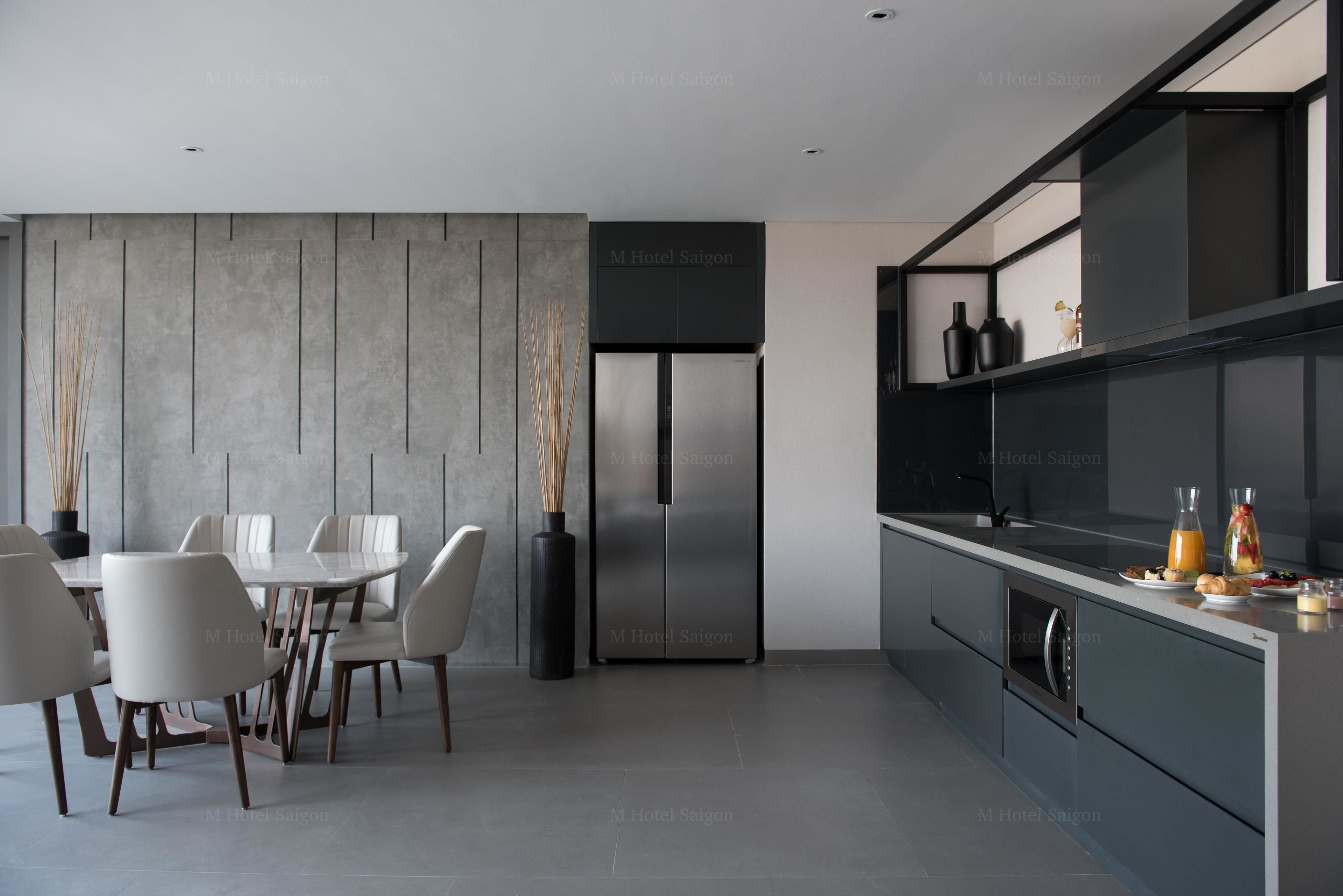 A modern kitchen with a built-in refrigerator, a dining area with a table and chairs, and a bar area with a counter and stools.