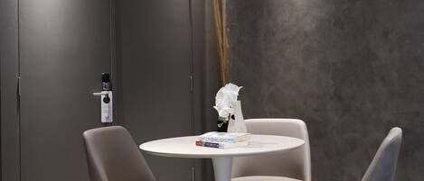 A modern room with a round table and two chairs, a vase with a white flower, and a door with a lock.