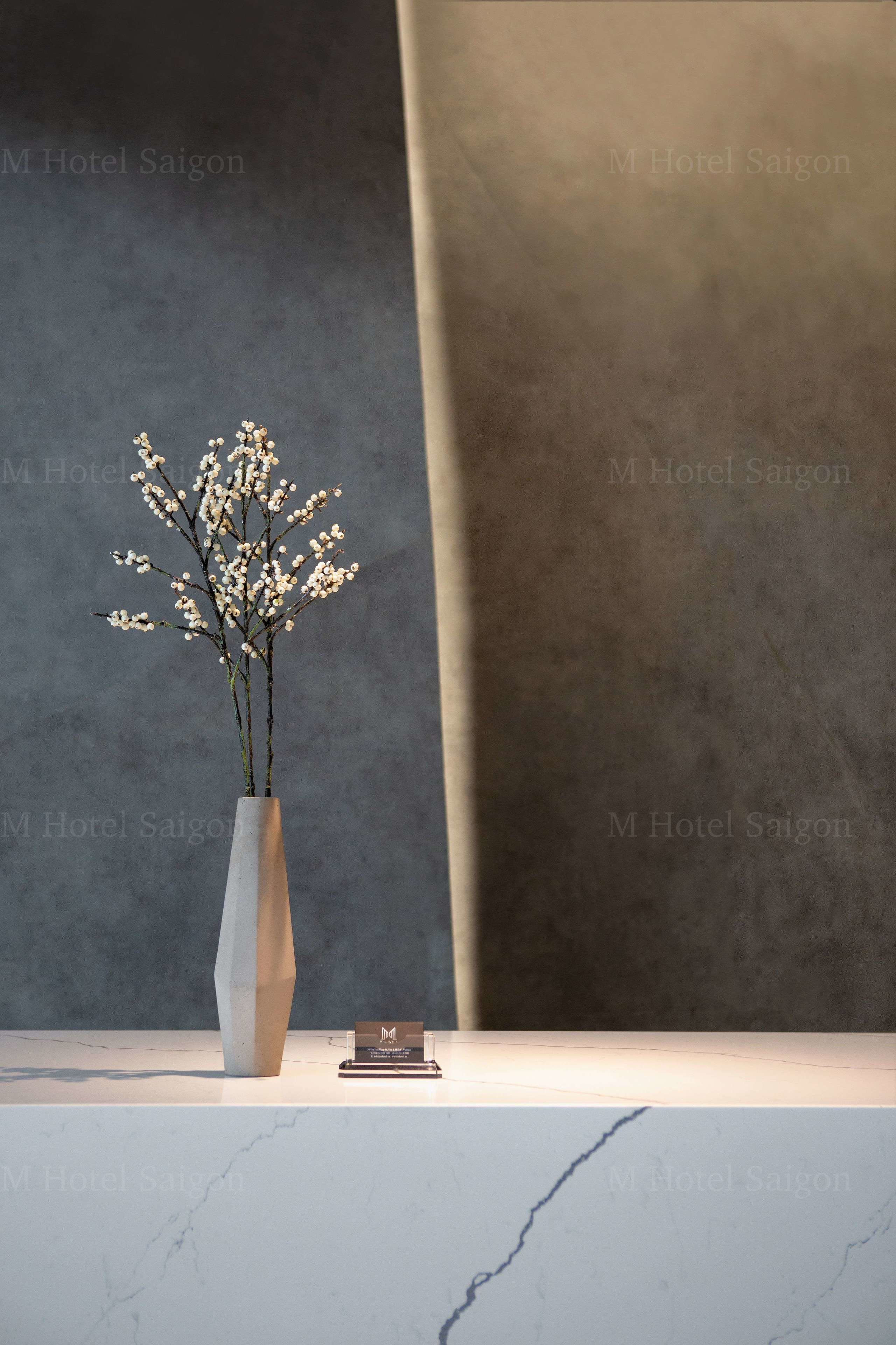 A vase with flowers on a marble surface next to a business card.