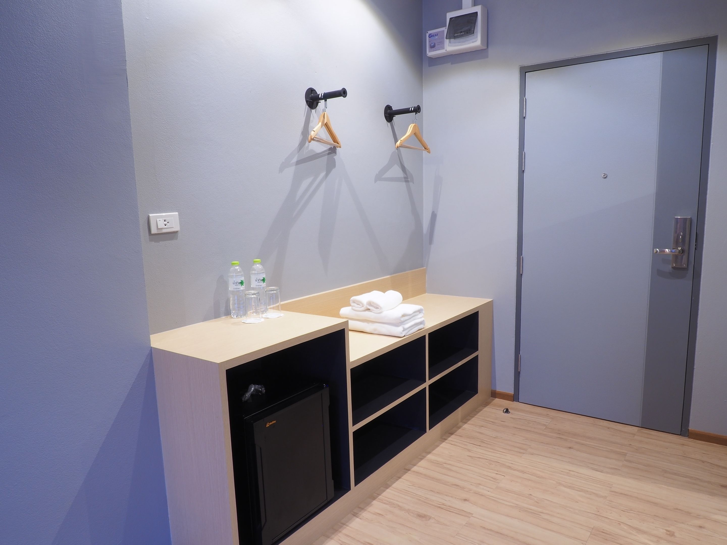 Un baño moderno con tocador de madera, un refrigerador pequeño y un perchero para toallas.