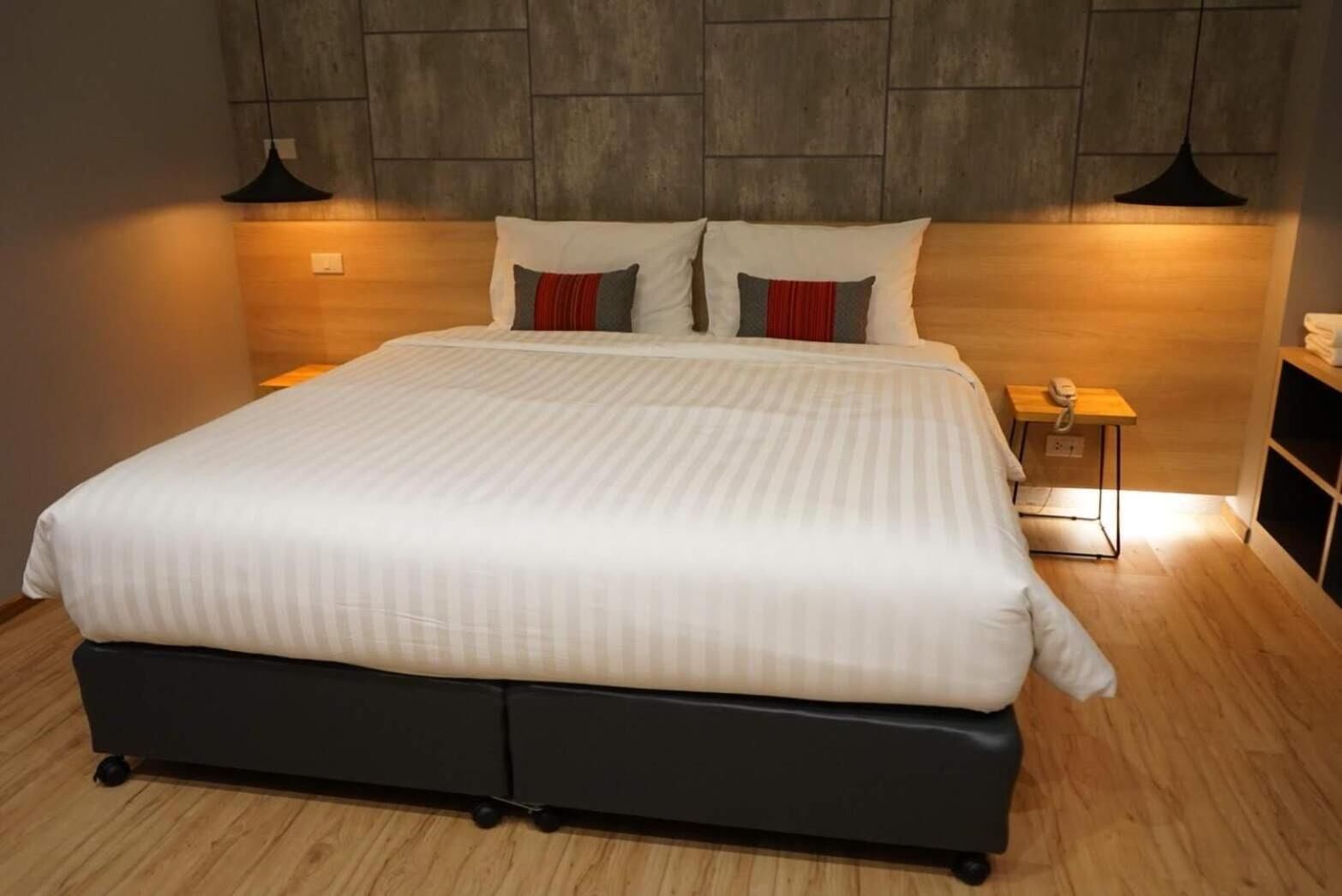 Un dormitorio moderno con una cama grande, cabecera con diseño texturizado y dos lámparas de noche.