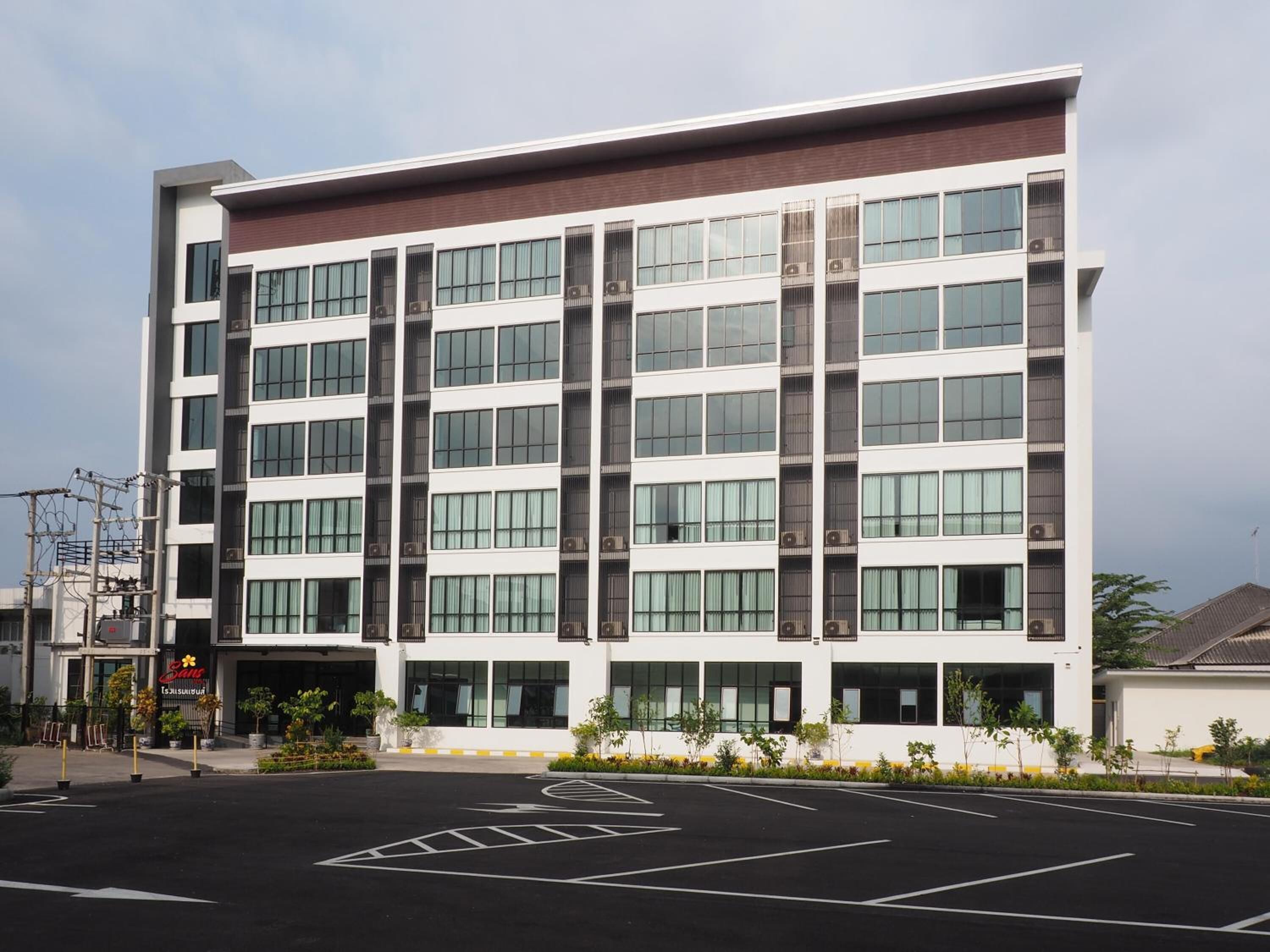 A modern multi-story hotel with a flat facade, large windows, and a parking lot in front.