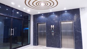 A modern elevator with marble walls and a glass door. - Sans Hotel (Ratchaburi)