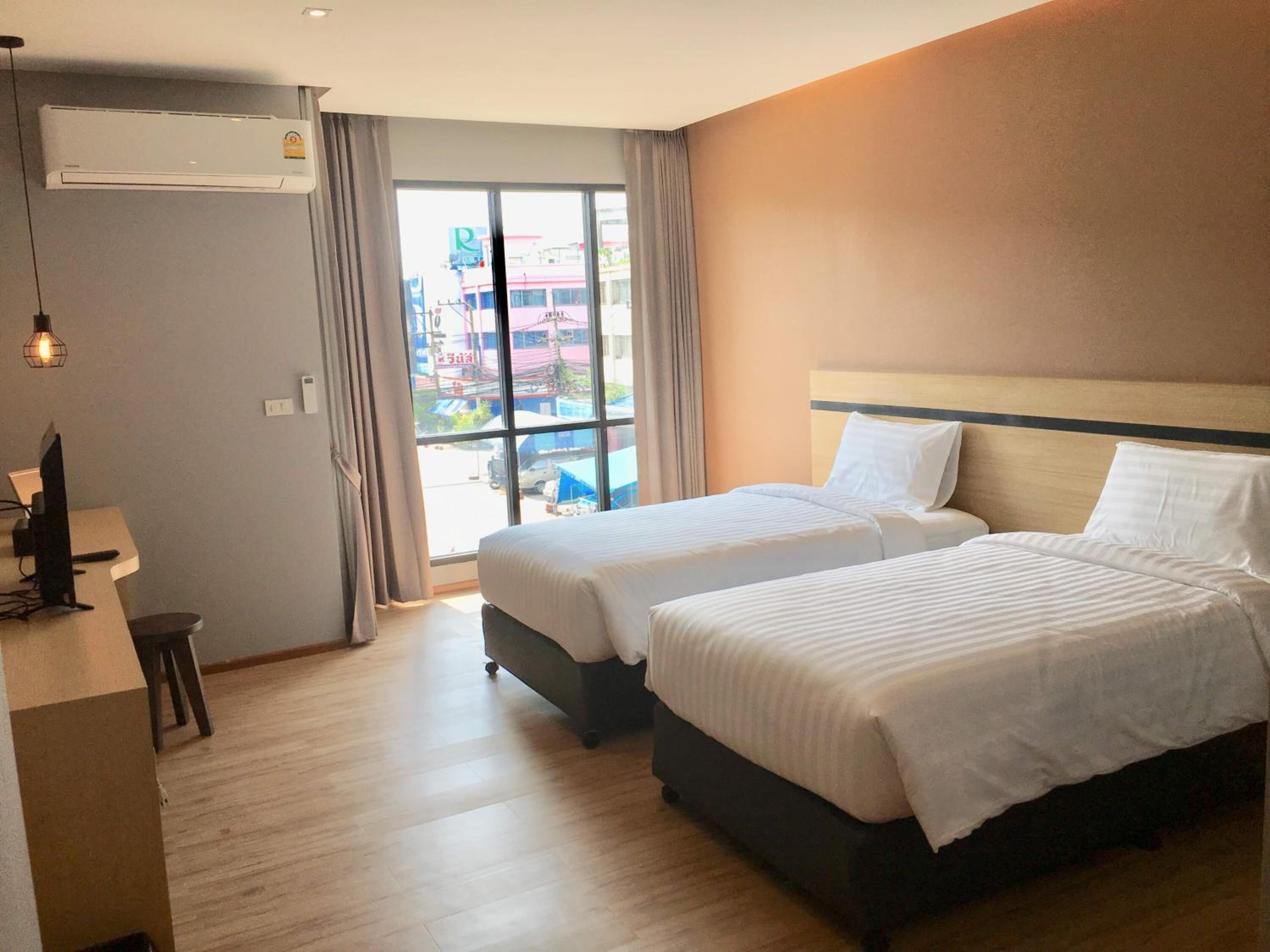 Habitación de hotel con dos camas, un escritorio y un equipo de aire acondicionado.