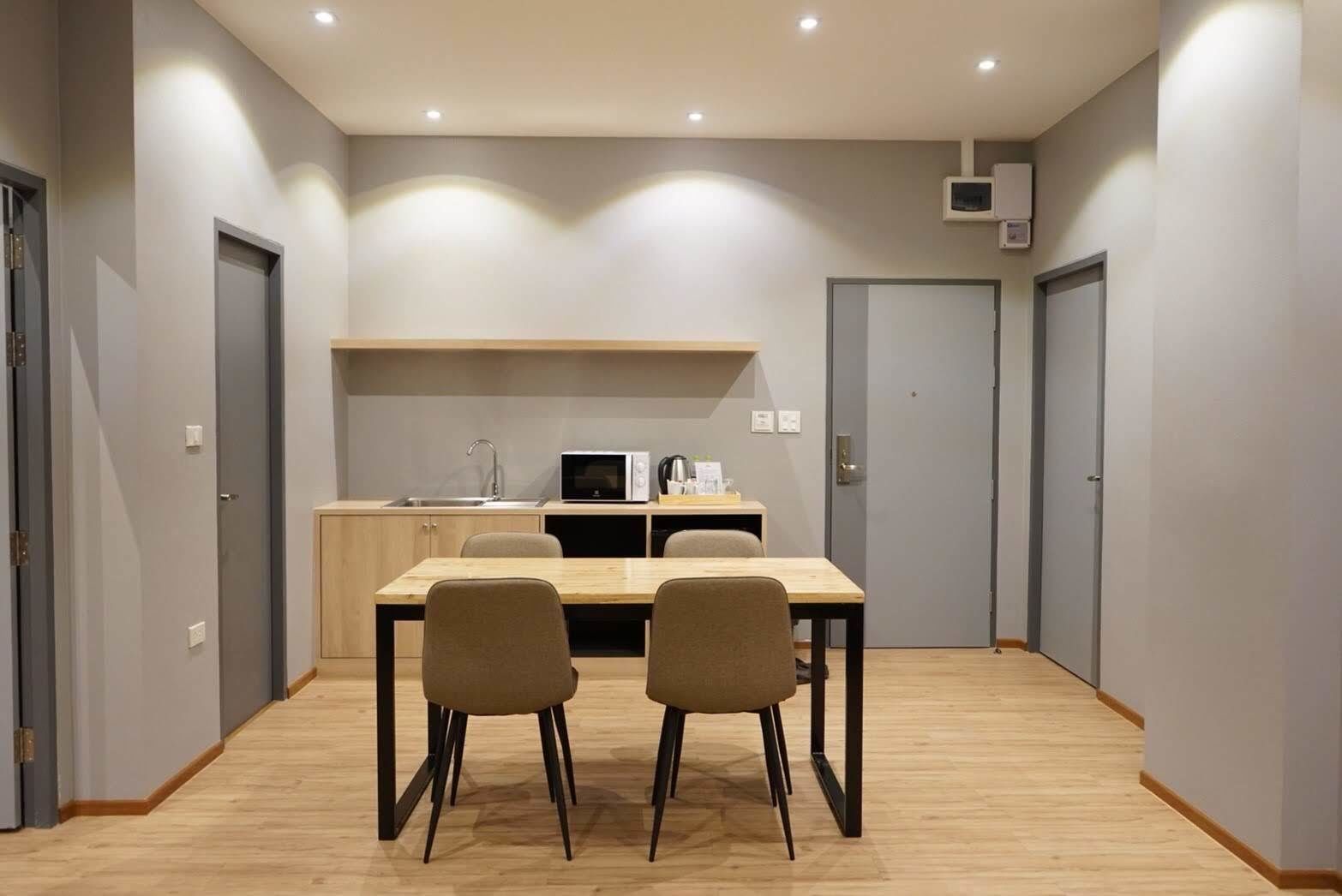 Cocina moderna con microondas, pileta y muebles bajos, comedor con mesa y sillas, y un pasillo con puertas.