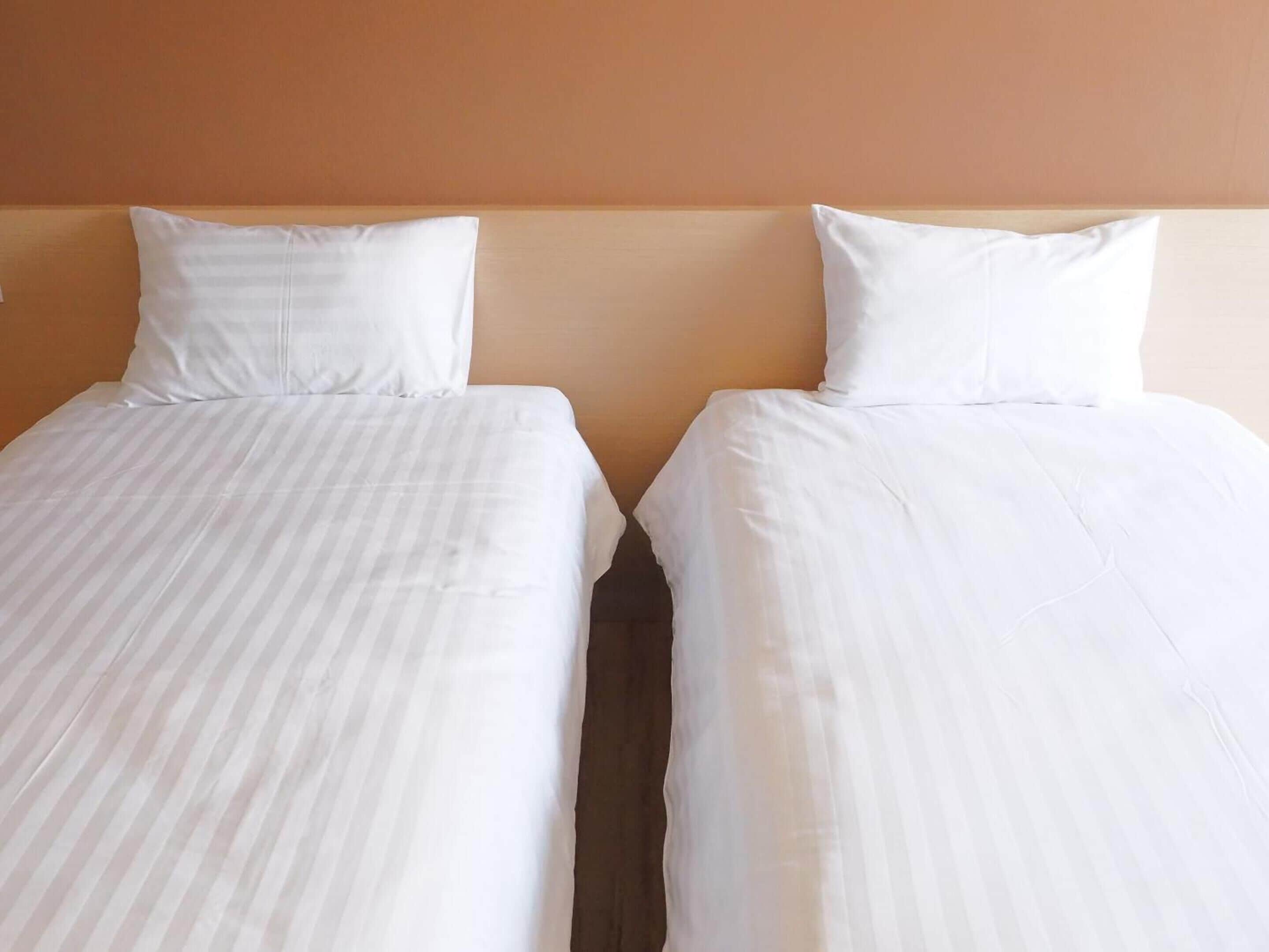 Two single beds with white linens and a wooden headboard.