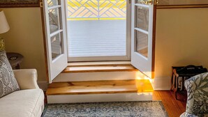 Een geopende deur die leidt naar een balkon met uitzicht op het strand en een houten terras.
