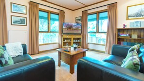 A living room with a television, two sofas, a coffee table, and a bookshelf. - A lovely rustic cottage with all the modern conveniences (Gawler South)