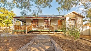 A two-story house with a porch, wooden deck, and a small garden area. - A lovely rustic cottage with all the modern conveniences (Gawler South)