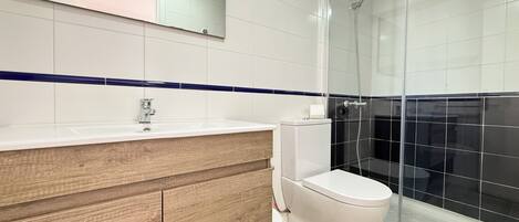 A modern bathroom with a wooden vanity, white sink, and a glass shower enclosure.