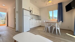 Une cuisine moderne avec des armoires blanches, un four à micro-ondes encastré et un coin repas comprenant une table et des chaises.