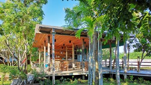 A wooden structure with a covered outdoor area, surrounded by greenery and trees. - Veepana Resort (Ban Laem)