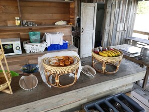 A rustic outdoor dining area with wicker baskets containing food items, a microwave, and various kitchen utensils. - Veepana Resort (Ban Laem)