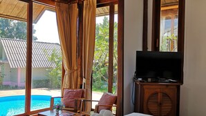 A hotel room with a bed, a TV, a pool view, and a wooden ceiling. - Veepana Resort (Ban Laem)
