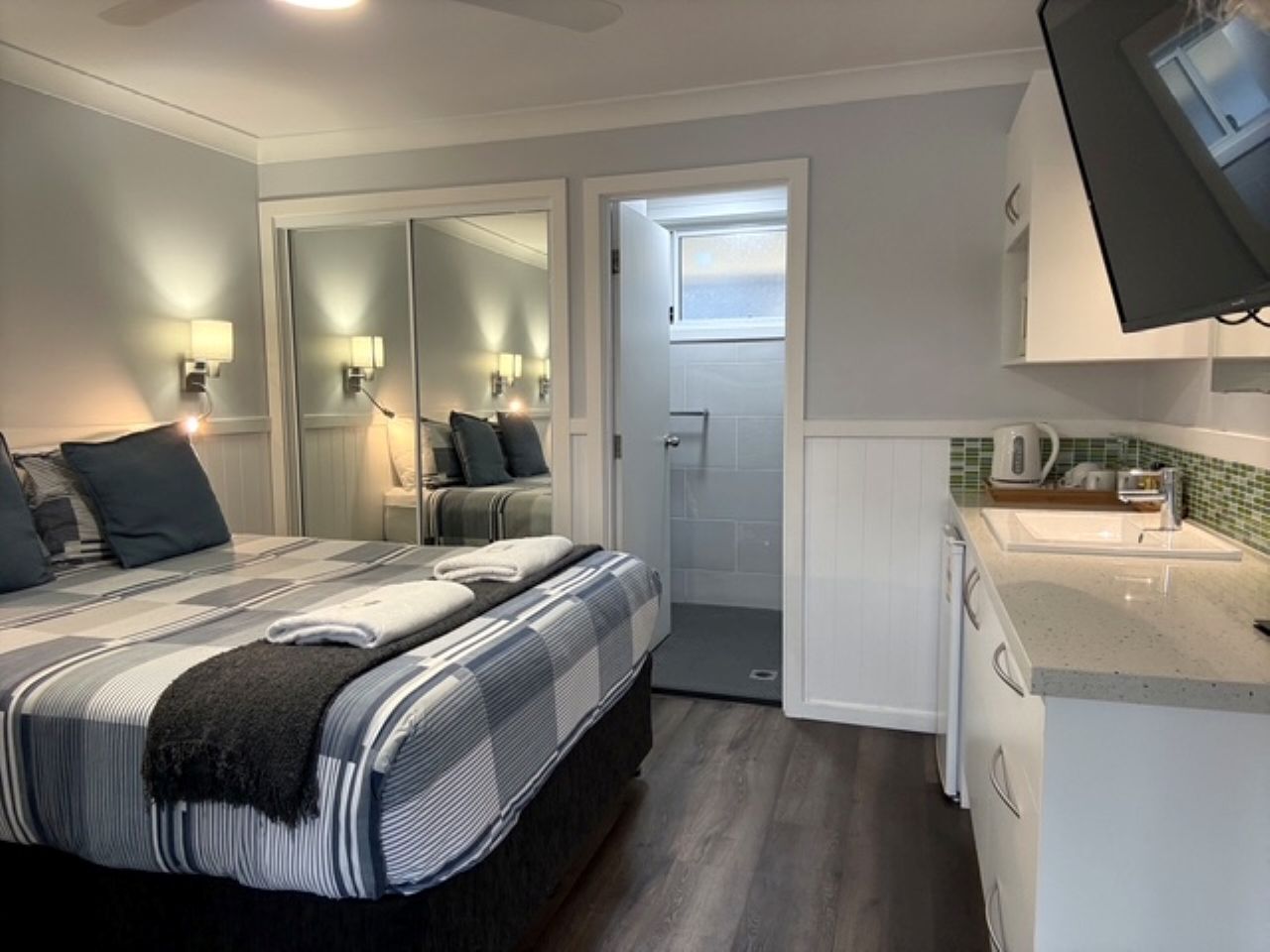 A bedroom with a bed, bedside lamps, a walk-in closet, and a bathroom with a shower.