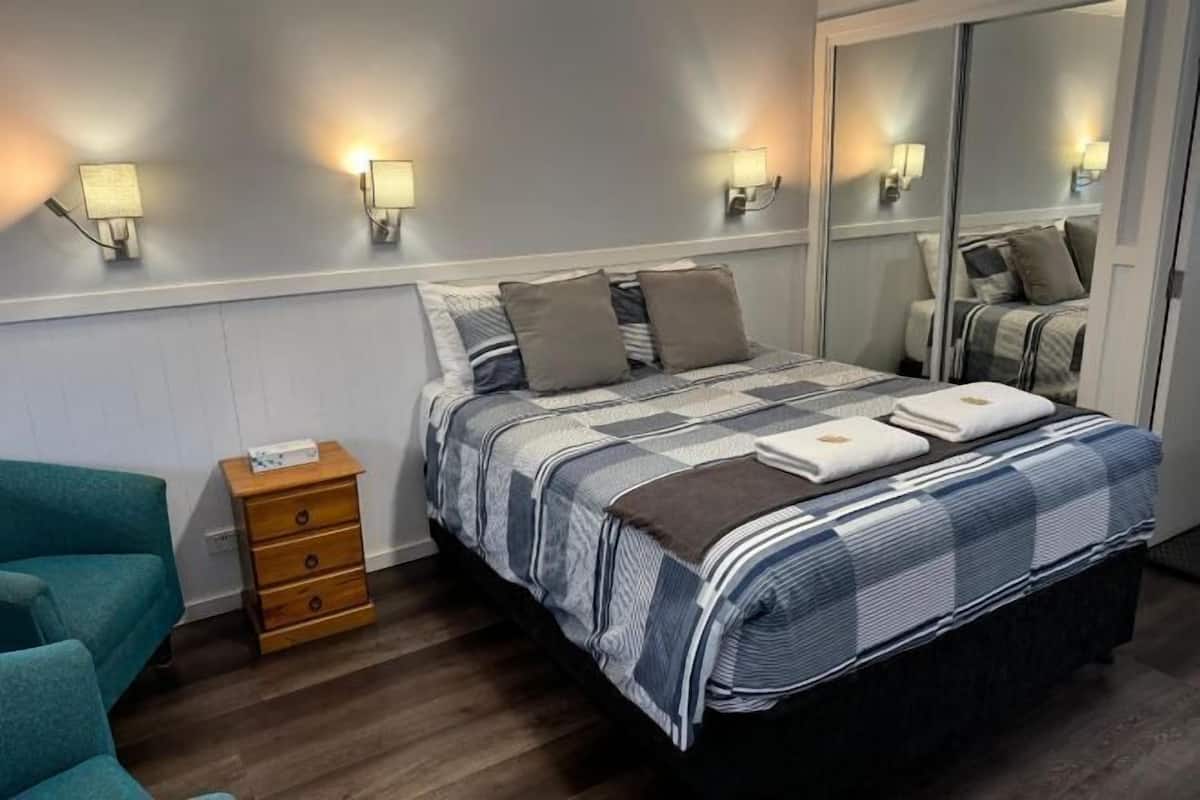 A bedroom with a bed, bedside tables, a dresser, and wall-mounted lamps.