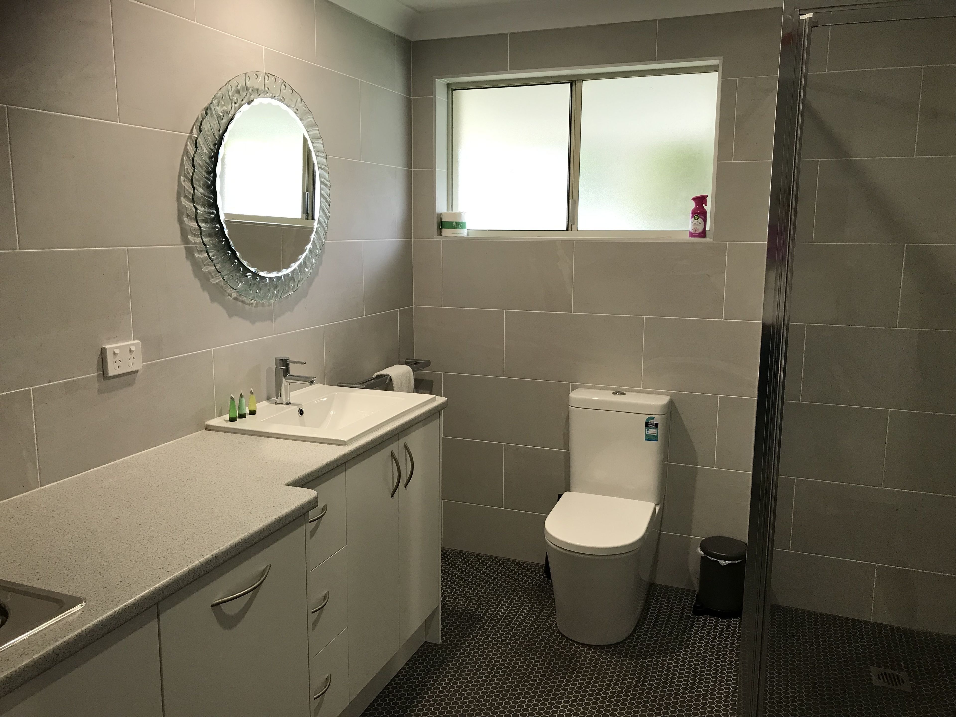 A bathroom with a sink, mirror, toilet, and shower.
