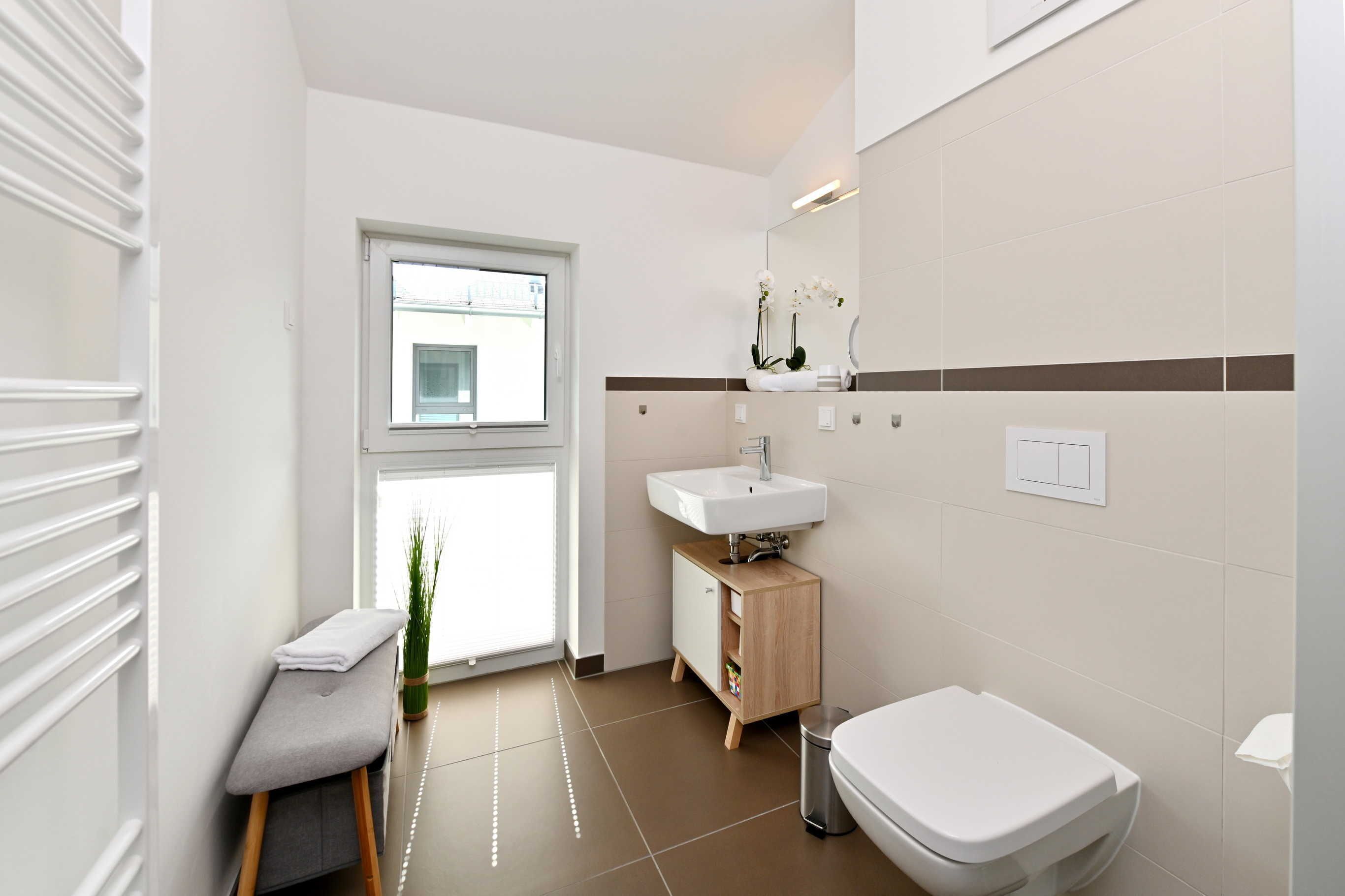 Un bany modern amb finestra, un lavabo, un vàter i un petit armari.