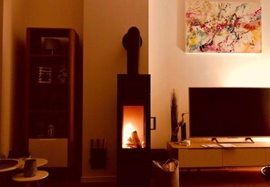 Ein gemütliches Wohnzimmer mit Kamin, Bücherregal, Flachbildfernseher und einem Bild an der Wand.