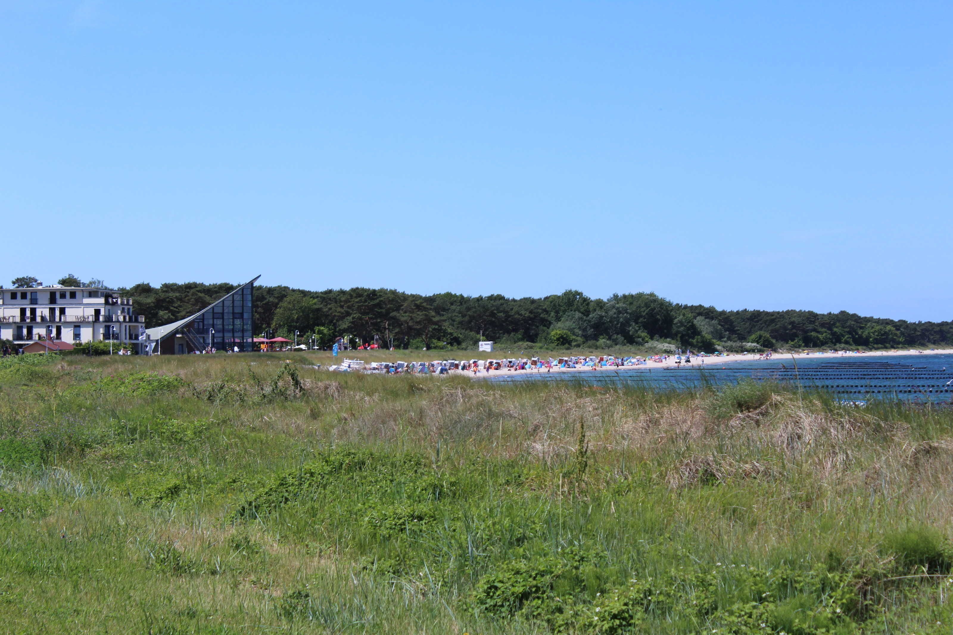 Ein Strand mit einem modernen Gebäude im Hintergrund.